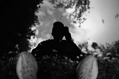 Rear view of silhouette woman sitting on field against sky