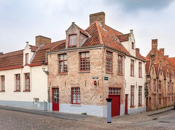 Footpath by buildings in city against sky