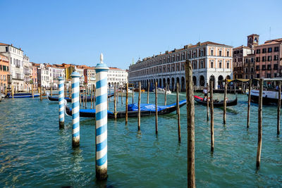 View of boats in canal by buildings against clear sky