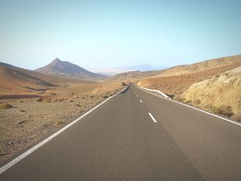 Empty road amidst landscape against clear sky