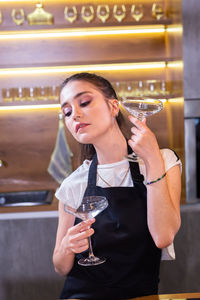 Young woman drinking water while standing in cafe