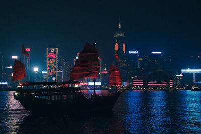 Boat in river by city at night