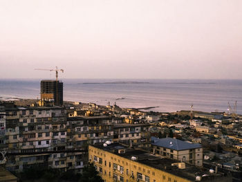 High angle view of townscape by sea against clear sky