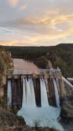 High angle view of long lake dam against sky during sunset