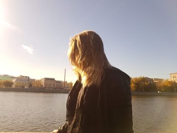 Rear view of woman against river in city