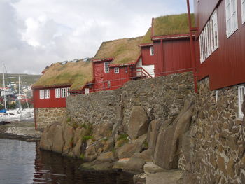 Houses by river amidst buildings against sky