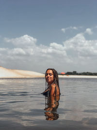 Portrait of smiling young woman standing against sky