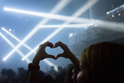 Close-up of person making heat shape at musical concert