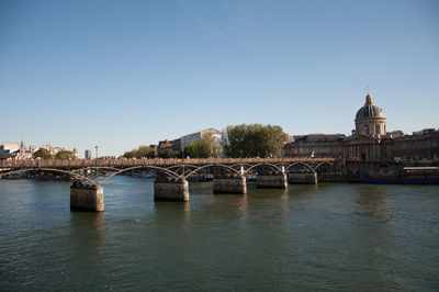 Bridge over river in city against clear sky