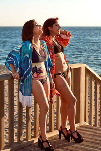 Two girls in bikinis posing on a staircase with the sea in the background. fashion concept