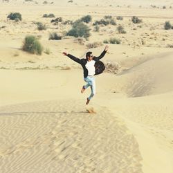 Full length of man jumping over sand at beach