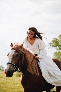 Young woman riding horse on field