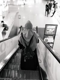 Rear view of man and woman standing on escalator