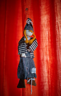 Close-up of toy hanging against red curtain