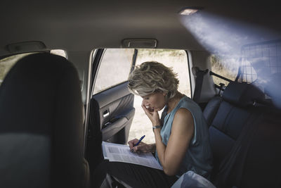 Side view of businesswoman writing on document car