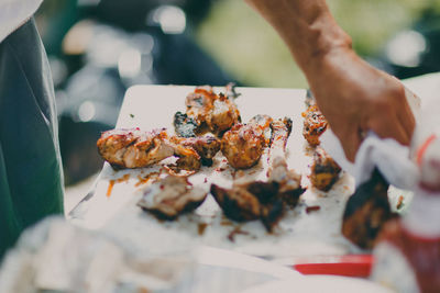 Cropped image of man holding grilled chicken meat at lawn