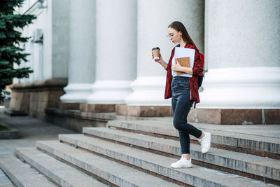 How to choose college or university. happy student girl with laptop and books near the university