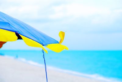 Yellow umbrella on beach against sky