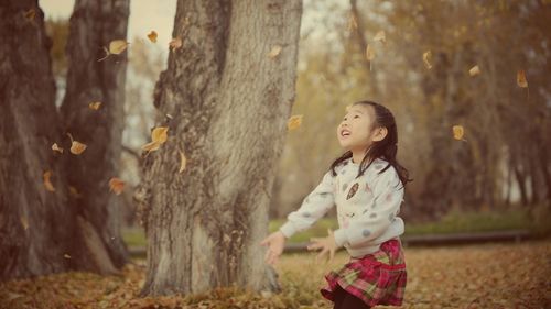 Cute girl playing with autumn leaves