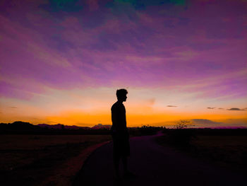 Silhouette man standing on field against sky during sunset