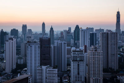 Modern buildings in city against sky during sunset