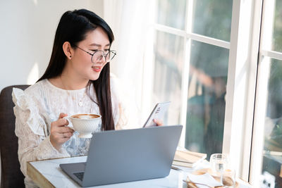 Woman looking away while sitting on window