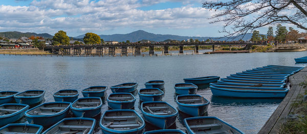 Panoramic view of rowboats in foreground and long bridge in the background