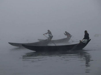 People in boat sailing on sea against sky