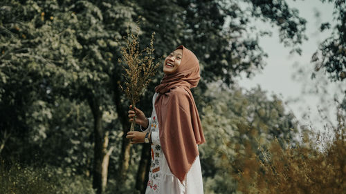 Rear view of woman standing by tree