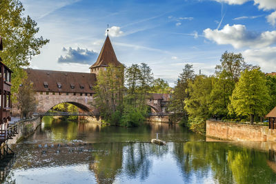 Arch bridge over river by building against sky