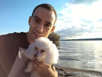 Portrait of young woman with dog against sea