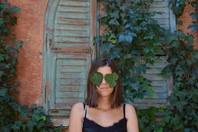 Portrait of young woman wearing sunglasses against plants