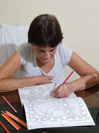 Woman drawing in book at home