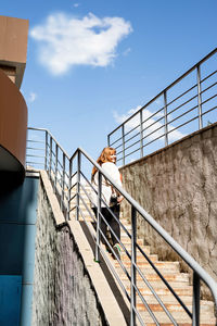 Low angle view of man standing on staircase against sky