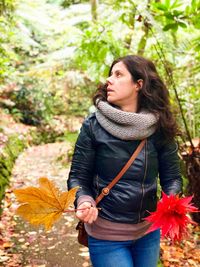 Beautiful young woman standing in autumn leaves