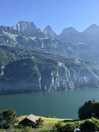 Scenic view of lake by mountains against blue sky