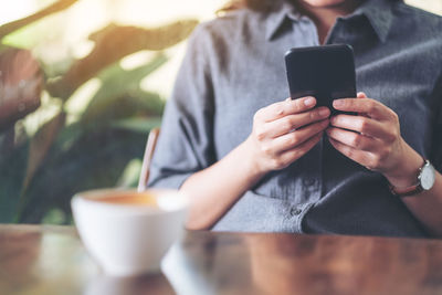 Midsection of woman using mobile phone at cafe