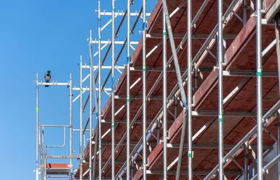 Low angle view of construction site against clear blue sky