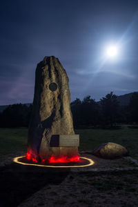Sculpture of rock on field against sky at night
