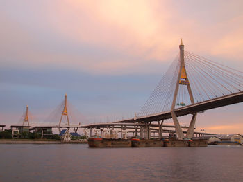 Suspension bridge over river during sunset