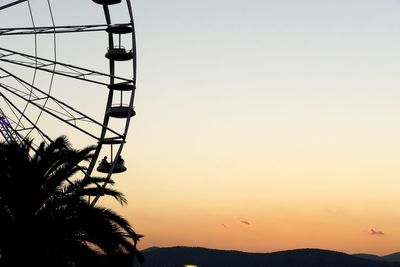 Cropped ferris wheel against sky during sunset