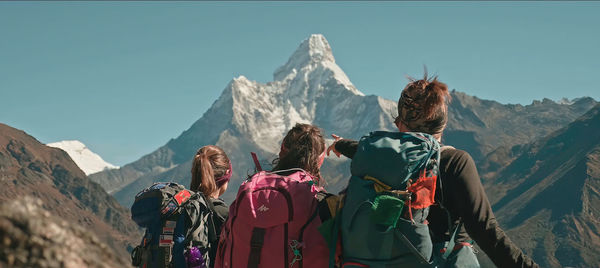 Rear view of people on mountains against sky