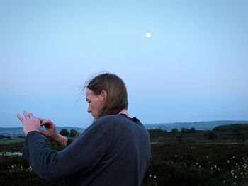 Man photographing on field against sky at dusk