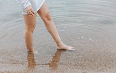 Low section of woman standing in water