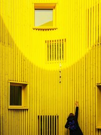 Full length of woman standing against yellow building
