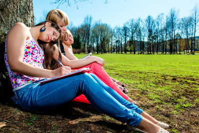 Young woman sitting on field in park