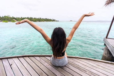 Rear view of woman standing in sea against sky