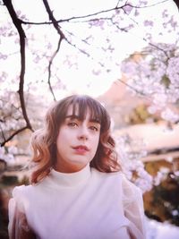 Portrait of a smiling girl standing by cherry tree