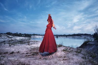 Rear view of woman standing at beach against sky