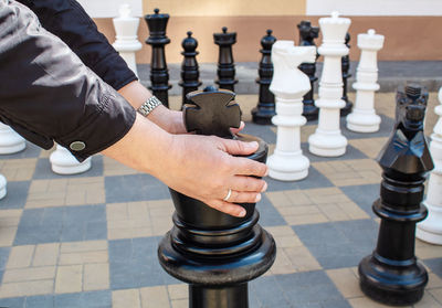 Cropped hands holding chess pieces on table